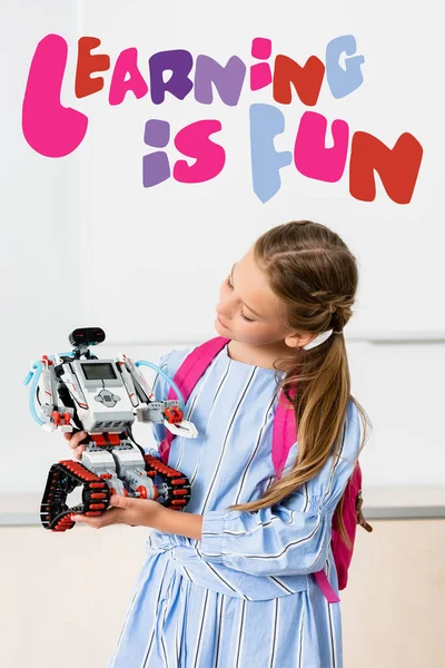 Schoolgirl holding robot near learning is fun illustration — Stock Photo