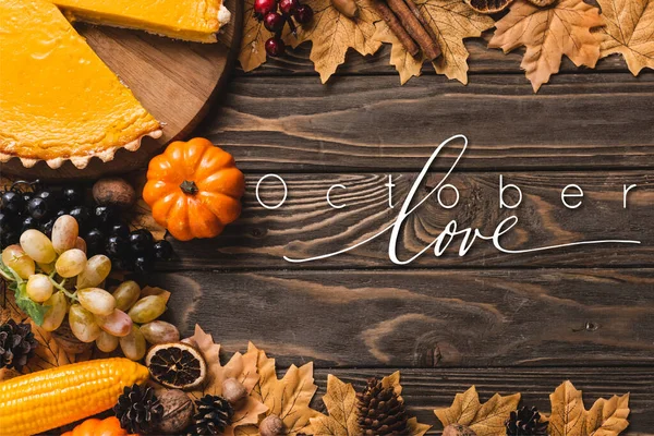 Top view of autumnal decoration and pumpkin pie near october love lettering on wooden background — Stock Photo