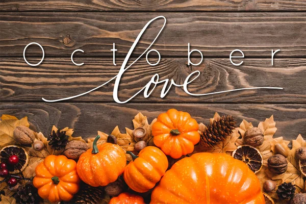 Top view of autumnal decoration and pumpkins near october love lettering on wooden background — Stock Photo