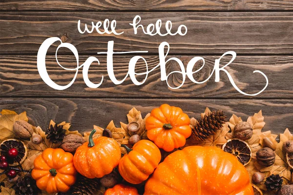 Top view of autumnal decoration and pumpkins near well hello october lettering on wooden background — стоковое фото