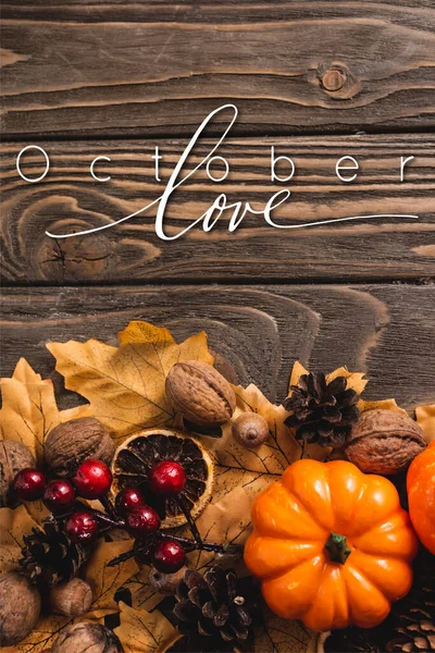 Vista superior de la decoración otoñal y calabaza cerca de octubre letras de amor sobre fondo de madera - foto de stock