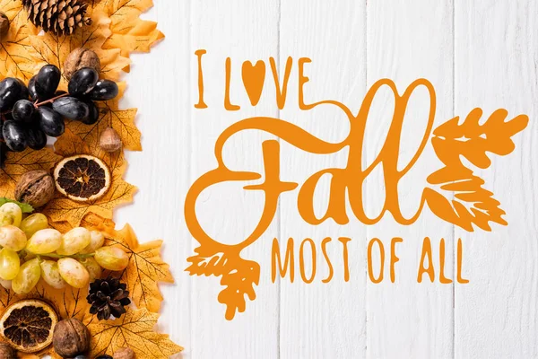 Draufsicht auf herbstliche Dekoration und Trauben in der Nähe Ich liebe den Herbst am meisten Schriftzug auf weißem Holzgrund — Stockfoto