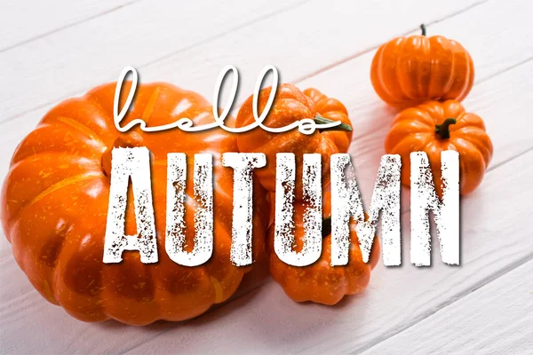 Orange pumpkins near hello autumn lettering on white wooden background — Stock Photo