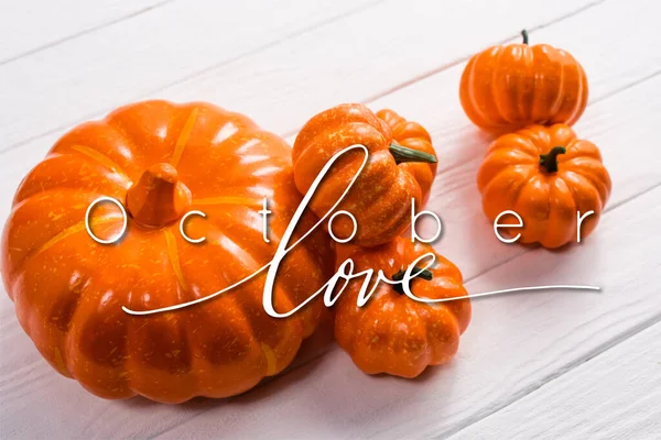 Orange pumpkins near october love lettering on white wooden background — Stock Photo