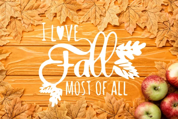 Top view of ripe apples and autumnal foliage near i love fall most of all lettering on wooden background — Stock Photo