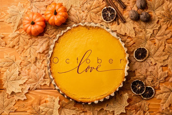 Vue du dessus de tarte à la citrouille avec décoration automnale près d'octobre amour lettrage sur fond en bois — Photo de stock