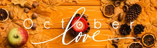 Top view of burning candle with autumnal decoration near october love lettering on wooden background, panoramic crop — Stock Photo