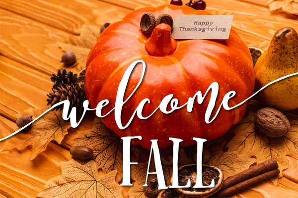 Pumpkin with autumnal decoration and happy thanksgiving card near welcome fall lettering on wooden background — Stock Photo