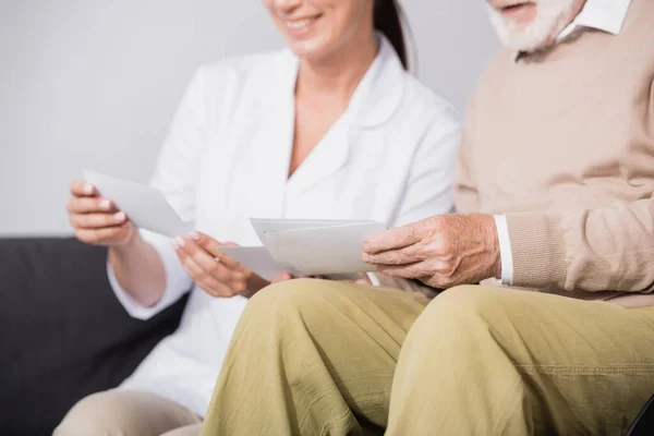 Social worker showing photos to aged man on blurred background — Stock Photo