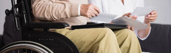 Cropped view of disabled man looking at photos with social worker, banner — Stock Photo