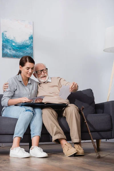 Elderly man and adult daughter looking at family photos together — Stock Photo