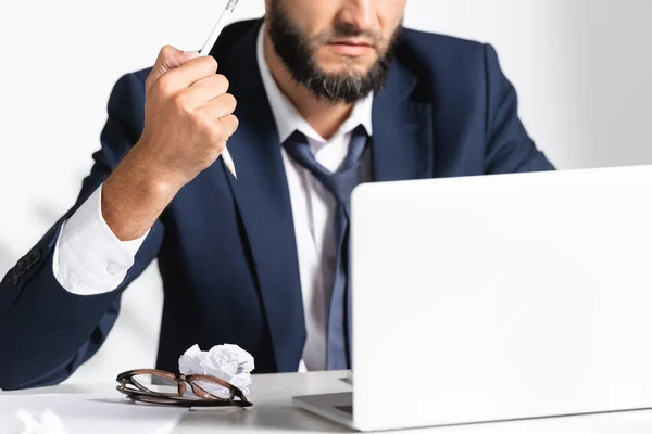 Cropped view of stressed businessman holding broken pencil near eyeglasses, laptop and clumped paper in office — Stock Photo