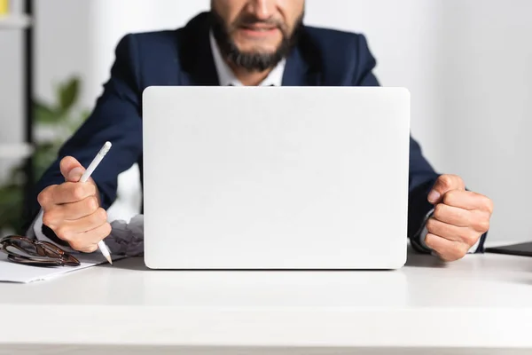 Ausgeschnittene Ansicht eines gestressten Geschäftsmannes mit gebrochenem Bleistift in der Nähe von Brille und Laptop auf dem Bürotisch — Stockfoto