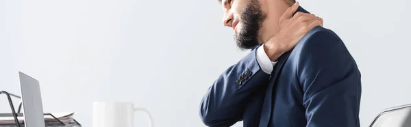 Businessman suffering from neck pain near laptop and cup on blurred foreground, banner — Stock Photo