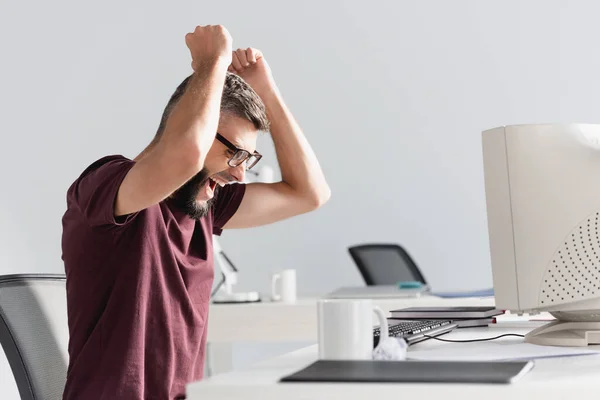 Gestresster Geschäftsmann schreit neben Computer und Schreibwaren auf verschwommenem Tisch — Stockfoto