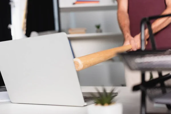 Ausgeschnittene Ansicht eines Geschäftsmannes mit Baseballschläger in der Nähe von Laptop mit verschwommenem Vordergrund in Bürotisch — Stockfoto