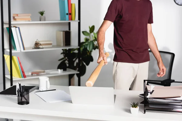 Vista cortada de empresário segurando taco de beisebol perto de laptop e papelaria na mesa — Fotografia de Stock