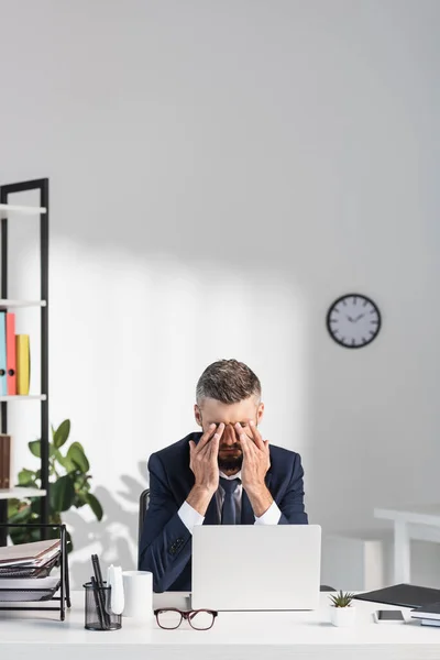 Geschäftsmann leidet unter Augenschmerzen in der Nähe von Geräten und Papieren im Büro — Stockfoto