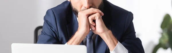 Vista ritagliata di uomo d'affari seduto vicino al computer portatile in primo piano sfocato in ufficio, banner — Foto stock