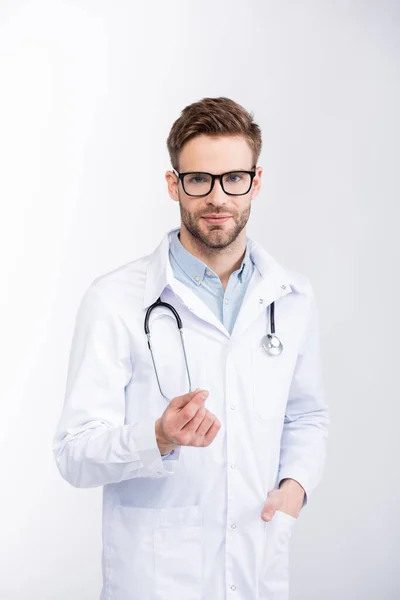 Oftalmólogo positivo con la mano en el bolsillo usando anteojos y mirando a la cámara aislada en blanco — Stock Photo