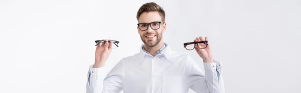 Front view of cheerful doctor with hands in air showing pair of eyeglasses, while looking at camera isolated on white, banner — Stock Photo