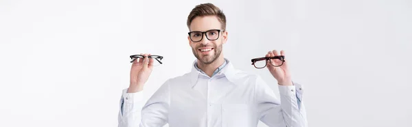 Vista frontale del medico allegro con le mani in aria che mostra un paio di occhiali, mentre guarda la fotocamera isolata su bianco, banner — Foto stock