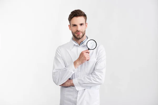 Vue de face de l'ophtalmologiste en manteau blanc avec loupe regardant la caméra isolée sur blanc — Photo de stock