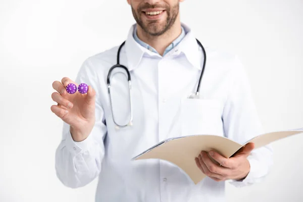 Ausgeschnittene Ansicht eines lächelnden Augenarztes mit Stethoskop, das Folder und Linsenbehälter auf weiß isoliert hält — Stockfoto