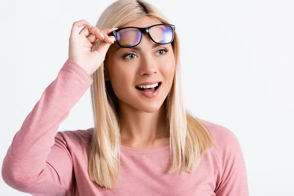 Захоплена молода жінка, дивлячись геть, тримаючи окуляри ізольовані на сірому — стокове фото