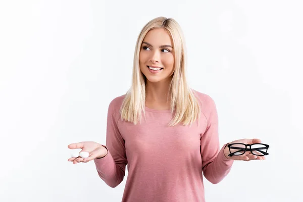 Donna positiva che distoglie lo sguardo mentre tiene la scatola con lenti a contatto e occhiali isolati su bianco — Foto stock