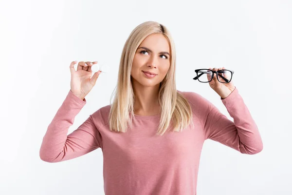 Mujer pensativa sosteniendo anteojos y contenedor con lentes de contacto aislados en blanco - foto de stock