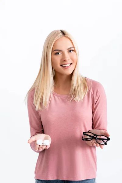Blonde Frau lächelt in die Kamera und hält Schachtel mit Kontakten und Brille isoliert auf weiß — Stockfoto