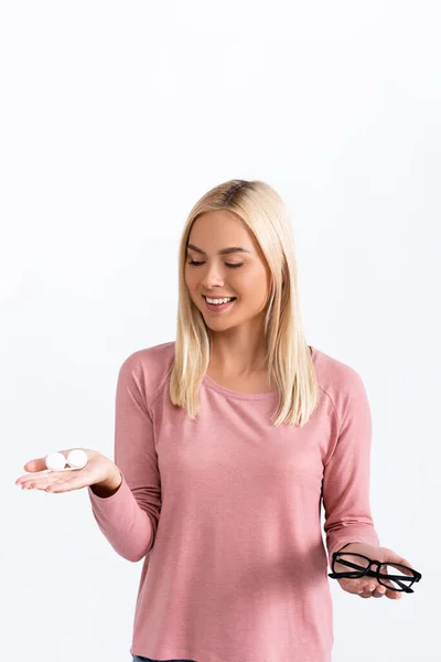 Mulher positiva segurando recipiente com lentes de contato e óculos isolados em branco — Fotografia de Stock
