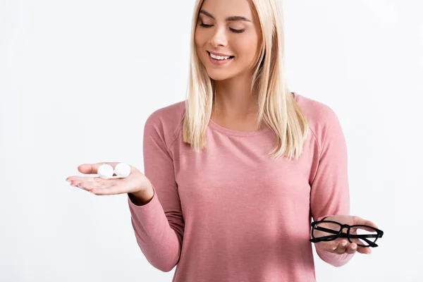Молода жінка дивиться на коробку з контактними лінзами, тримаючи окуляри ізольовані на білому — стокове фото