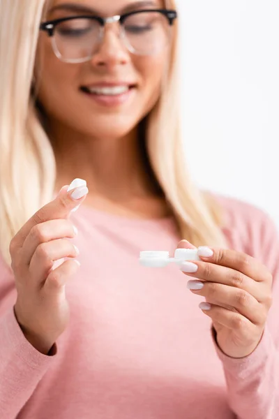 Tampa e recipiente com lentes de contato em mãos de mulher sorridente em óculos em primeiro plano desfocado isolado em branco — Fotografia de Stock