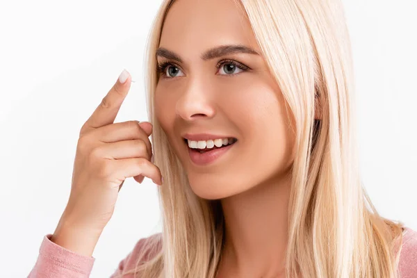 Positiva donna bionda tenendo la lente a contatto mentre distoglie lo sguardo isolato sul bianco — Foto stock