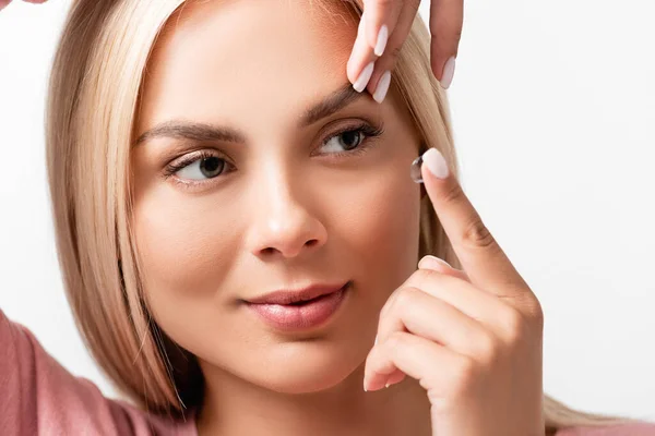 Femme blonde mettant lentille de contact dans l'oeil isolé sur blanc — Photo de stock