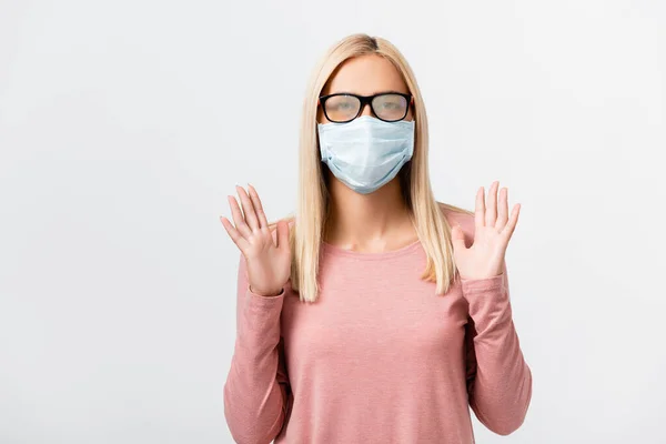 Молодая женщина в туманных очках и медицинской маске, стоящая изолированная на сером — стоковое фото