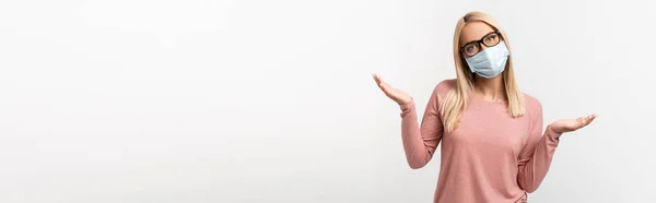 Verwirrte Frau mit Brille und medizinischer Maske zeigt achselzuckende Geste auf grauem Banner — Stockfoto