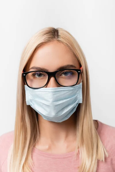 Ritratto di donna bionda in occhiali e maschera medica guardando la fotocamera isolata su grigio — Foto stock