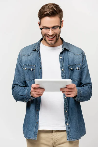 Positive man in eyeglasses using digital tablet isolated on grey — Stock Photo