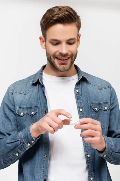 Giovane uomo sorridente che tiene il contenitore con lenti a contatto isolate su grigio — Foto stock