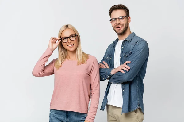 Pareja joven en gafas de vista sonriendo mientras mira a la cámara aislada en gris — Stock Photo