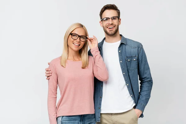 Smiling man in eyeglasses embracing girlfriend isolated on grey — Stock Photo