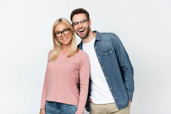 Alegre pareja en gafas de vista mirando a la cámara aislada en gris - foto de stock