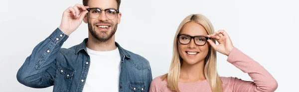 Pareja sonriente tocando anteojos aislados en gris, estandarte - foto de stock