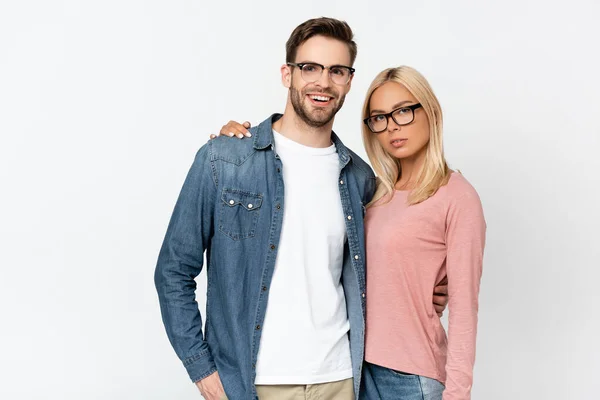 Femme blonde étreignant petit ami souriant dans des lunettes isolées sur gris — Photo de stock