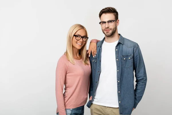 Lächelnde blonde Frau mit Brille umarmt Mann isoliert auf grau — Stockfoto