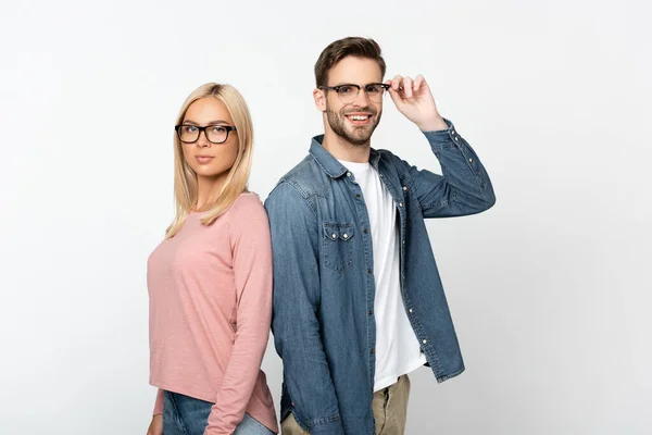 Uomo sorridente toccare occhiali ottici vicino fidanzata bionda isolato su grigio — Foto stock