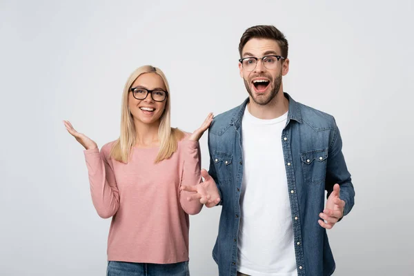 Joven pareja positiva en gafas de vista mirando a la cámara aislada en gris — Stock Photo